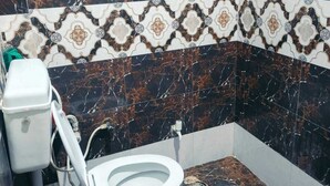 Ein Badezimmer mit Toilette, Marmorfliesen und einer gemusterten Fliesenleiste.