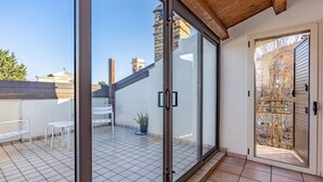 A room with a sliding glass door, a tiled floor, a small white table, and a potted plant.