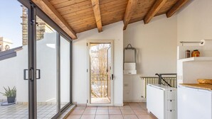 A modern kitchen with a sliding glass door leading to a balcony, a white cabinet, and a small refrigerator.
