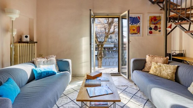 A modern living room with a sofa set, a coffee table, and a staircase.