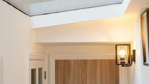 Ein modernes Interieur mit einer Holztür, einem Glasbalkon und einer wandmontierten Leuchte.