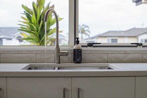 Een keuken met een rvs spoelbak, een kraan en een zeepdispenser.