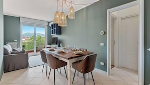 Un comedor con mesa preparada para cuatro, un sofá y un balcón con vistas.