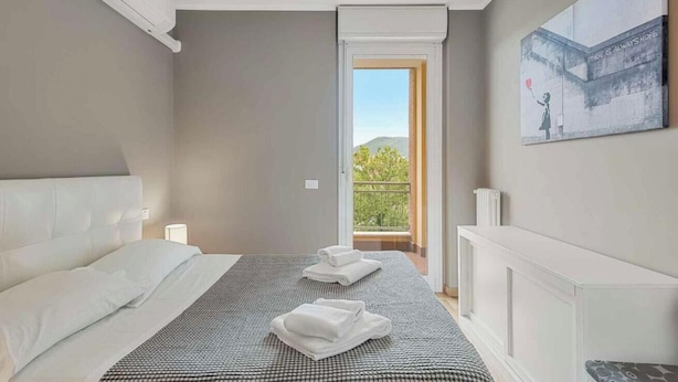 Un dormitorio con cama, dos toallas, ventana y balcón.