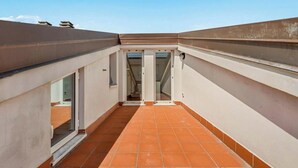 Un pasillo estrecho con suelo de baldosas y puertas de cristal que dan a una escalera.