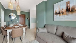 Una sala moderna con un sofá gris, una mesa de comedor con sillas y un cuadro en la pared.