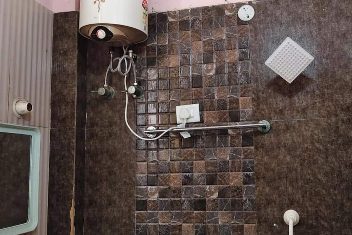 Een badkamer met een douche, een handgreep, een betegelde wand en een raam.