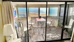 Ein Zimmer mit Balkon, Tisch, Stühlen und Meerblick.