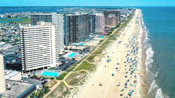 Eine Küstenstadt mit Wolkenkratzern, einem Strand und blauem Himmel.