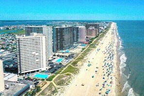 A coastal cityscape with high-rise buildings, a beach, and a clear sky. - Swanky 2 Bedroom Oceanfront Condo with Outdoor Pool, WiFi, and Great Beach View from open balcony. Linen & towels included.Vacation at the Shore with Shoreline Properties (Ocean City)