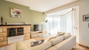 Ein Wohnzimmer mit Sofa, Fernseher, Kamin und einem Gemälde an der Wand.