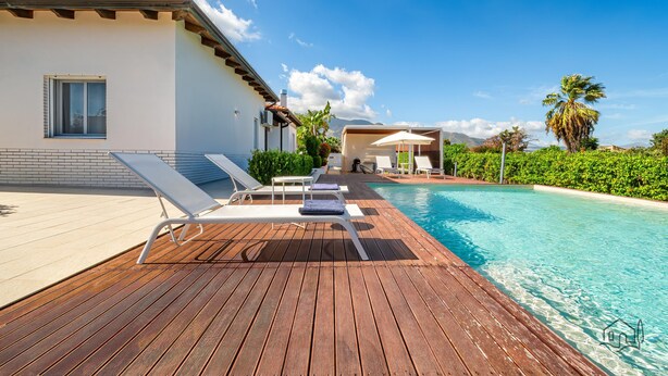 Eine Holzterrasse mit Liegestühlen und einem Swimmingpool.