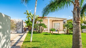 Ein modernes Haus mit gepflegtem Rasen, Palmen und blauem Himmel.