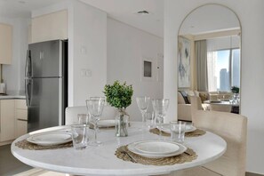 Un comedor moderno con una mesa redonda dispuesta para cuatro personas, una pequeña planta en maceta y vistas de la ciudad a través de un gran ventanal.