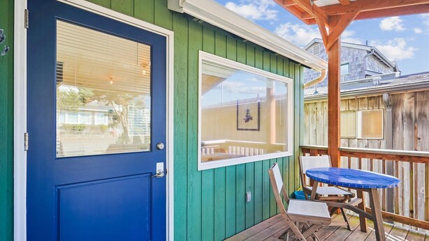 Um deck de madeira com uma porta azul e uma janela com moldura.