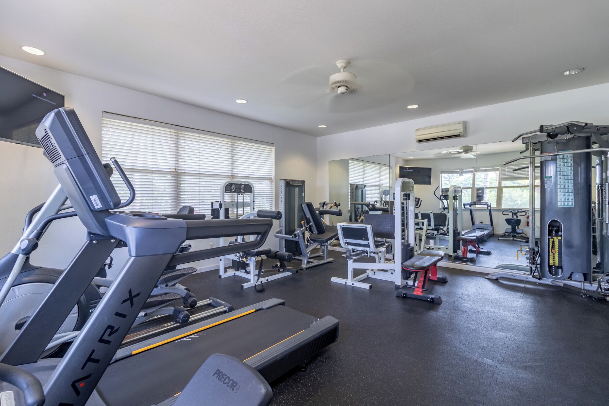 A gym with treadmills, weight machines, and a mirror wall.