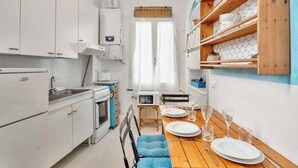 A compact kitchen with white cabinets, a microwave, and a dining area with a wooden table set for two. - Welcome to La Goletta, your holiday home on the third and top floor of a quiet building in La Spezia. This cozy two-room apartment is perfect for families, couples or small groups of friends.🛏 Sleeps up to 4 people with a double sofa bed in the living (La Spezia)