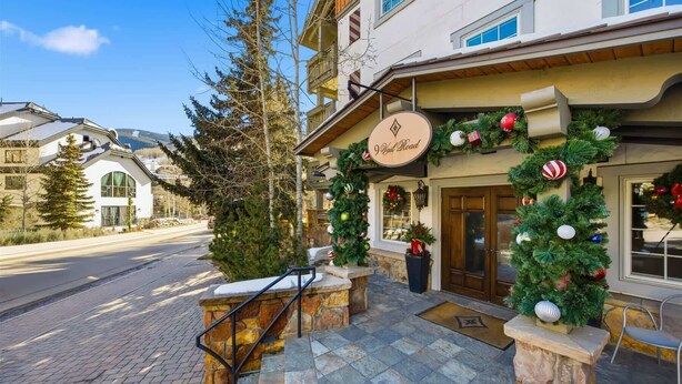 Een hotelentree met een stenen trap, een bord met daarop 'I Vall Road' en kerstversiering.