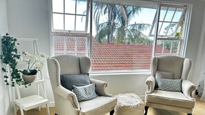 A room with two armchairs, a small white shelf, and a potted plant. - *New Collaroy 3 B/R Northern Beaches Spacious & Renovated Beach Getaway Collaroy (Collaroy)