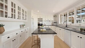 A modern kitchen with white cabinetry, a black countertop island, and a large window providing natural light. - *New Collaroy 3 B/R Northern Beaches Spacious & Renovated Beach Getaway Collaroy (Collaroy)