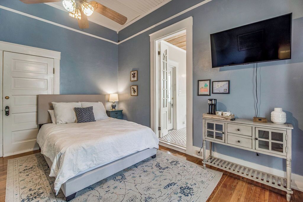 A bedroom with a bed, bedside tables, a TV, and a console table.
