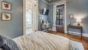 A bedroom with a bed, a dresser, a TV, and a window with curtains. - Pensacola • 1BR • Sleeps 2 • Close to Downtown (Pensacola)