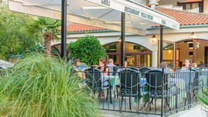 An outdoor seating area with tables and chairs, a Coca-Cola branded awning, and a sign for a restaurant named 'Villa Vrsar Grill'. - Hotel Villa Vrsar (Vrsar)