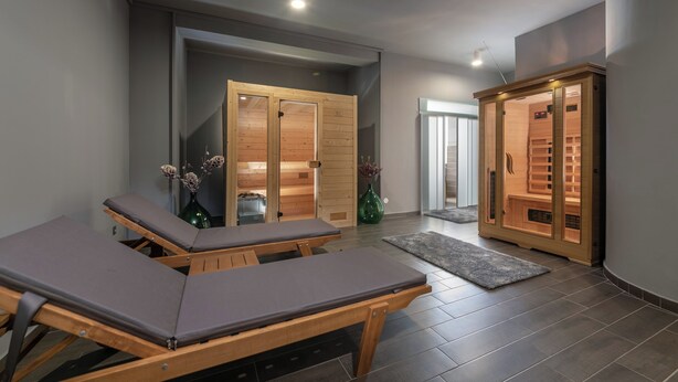 A spa room with wooden massage tables, a sauna, and a wooden cabinet with shelves. - Hotel Villa Vrsar (Vrsar)