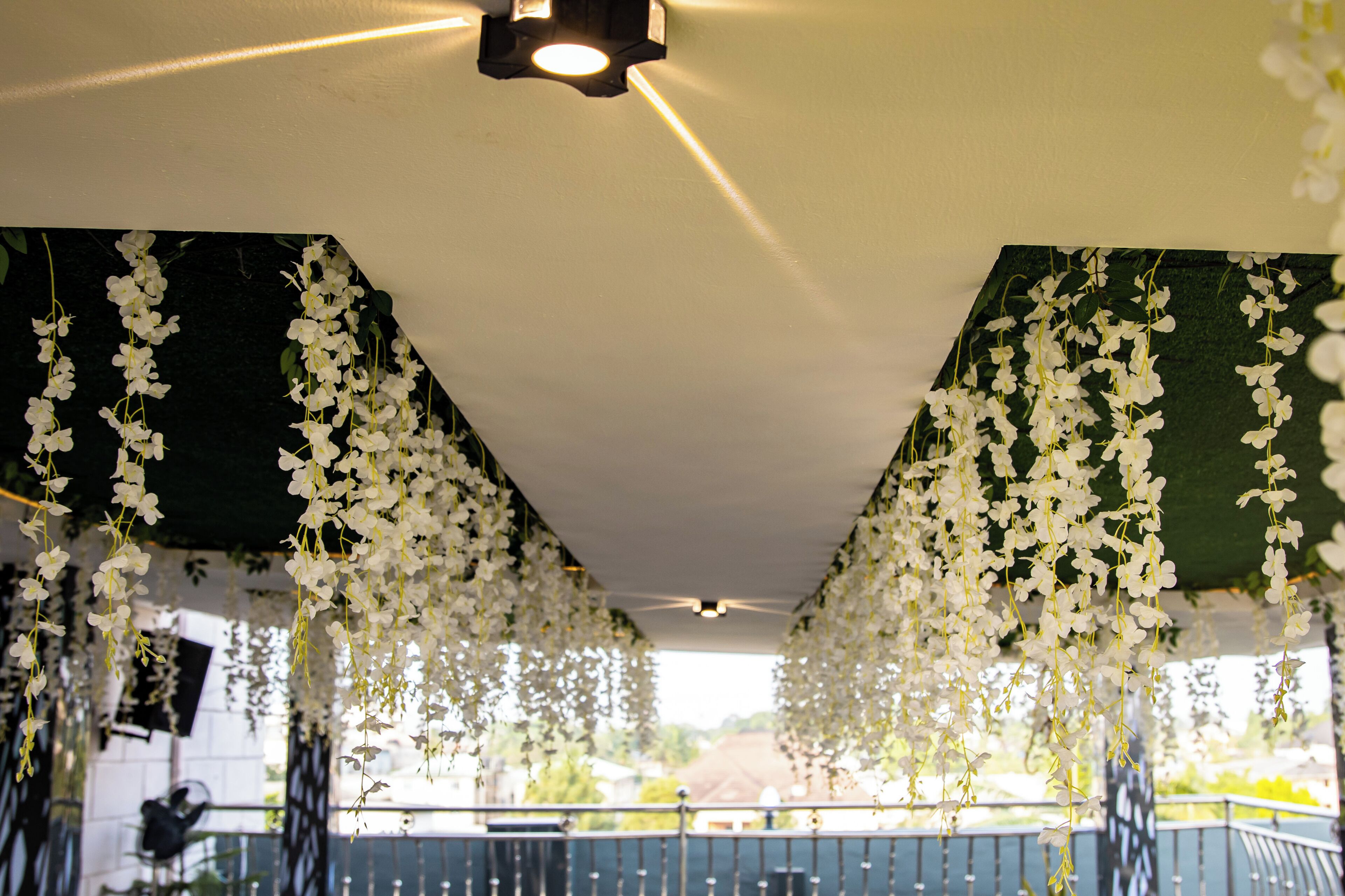 A room with hanging white flowers, a ceiling light, and a view of the outdoors.
