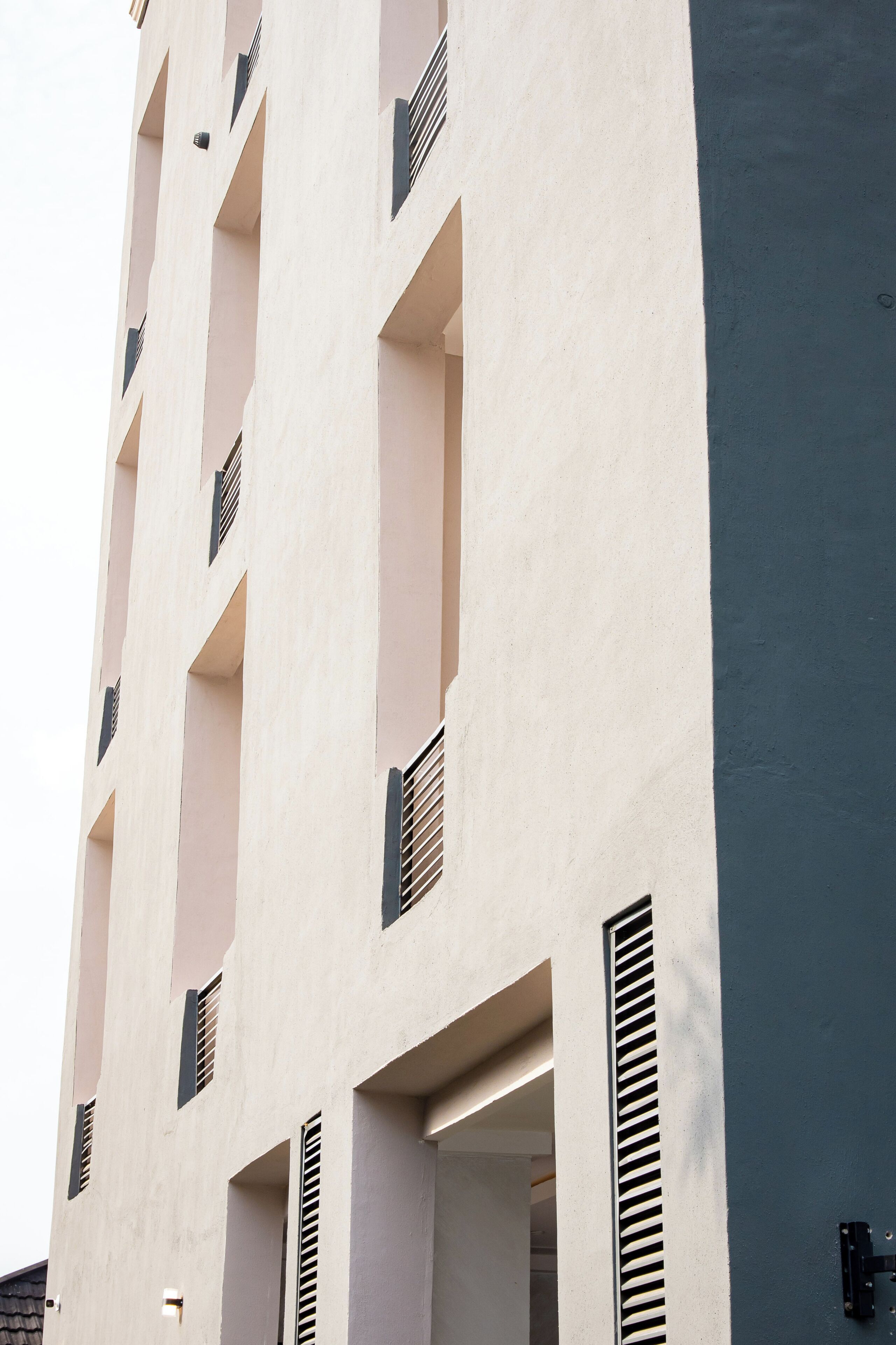 A multi-story building with balconies and ventilation slats.