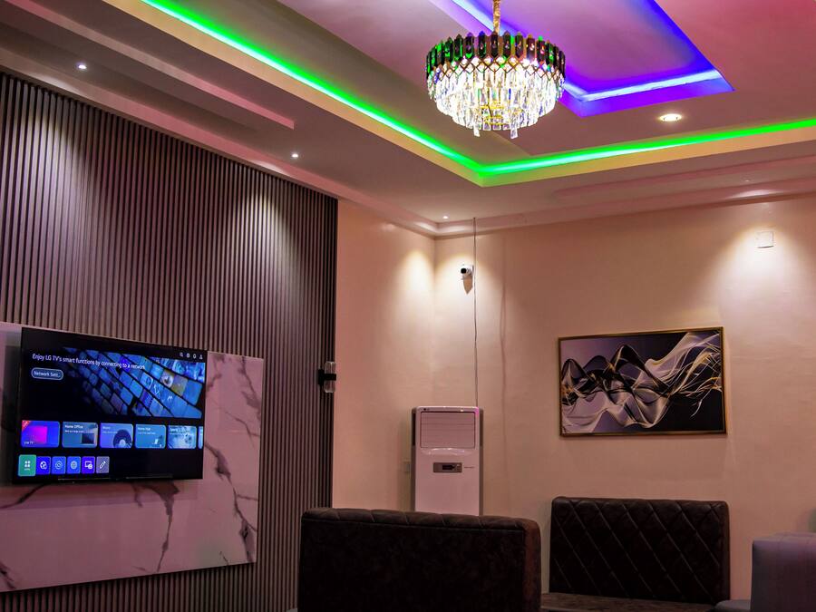 A modern room with a flat-screen TV, a chandelier, and a painting on the wall.