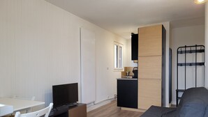 Un espacio habitable compacto con kitchenette, comedor y zona de estar.