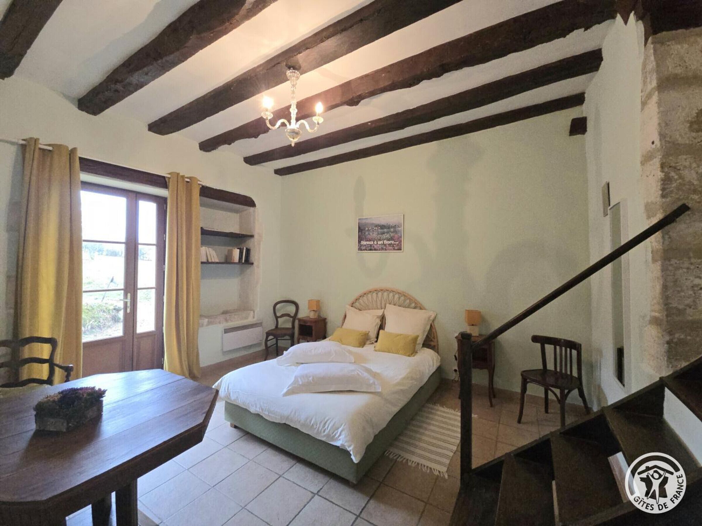 Un dormitorio con cama, escritorio, silla, estantería y escalera.
