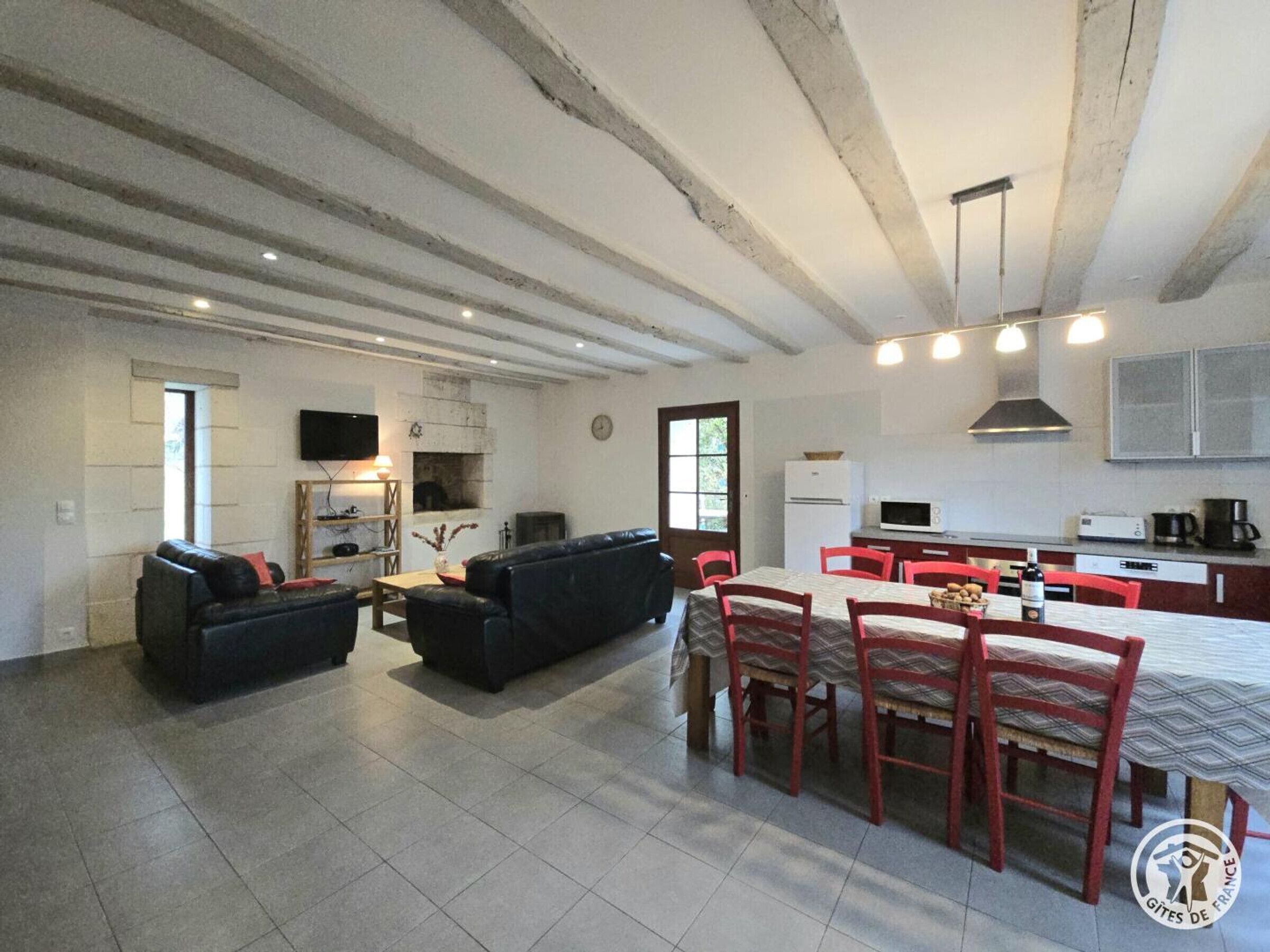Een ruime woonkamer met een zithoek, een eettafel met stoelen en een keuken met moderne apparatuur.