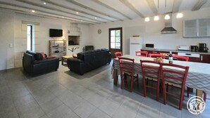 A spacious living area with a sofa set, a dining table with chairs, and a kitchen area with modern appliances. - Périgord Cottage with Garden, WIFI & Pets Welcome (Sorges et Ligueux en Périgord)
