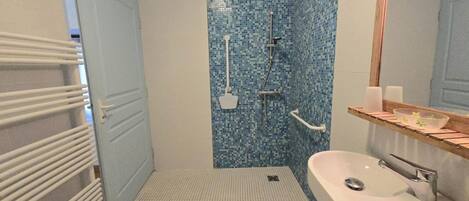 Een badkamer met een douche, een wastafel en een spiegel.