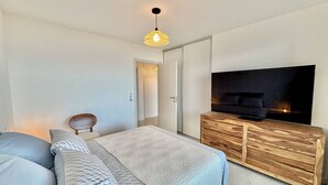 Una camera da letto moderna con un letto, una TV su un mobile in legno e un lampadario.