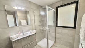 Un bagno moderno con doccia vetrata, un mobile lavabo con specchio e un appendi asciugamani.