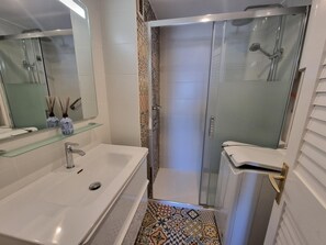 A bathroom with a white sink, mirror, and glass shower enclosure. - Cozy apartment in L'Escala with terrace near the beach (L'Escala)