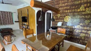 A dining area with a wooden table and chairs, a television, and a decorative wall. - Say Resort Morning Glory (Mal)