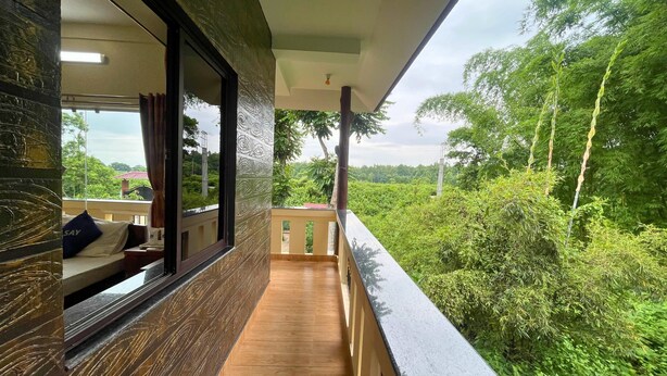 A balcony with a wooden floor and a view of lush greenery. - Say Resort Morning Glory (Mal)