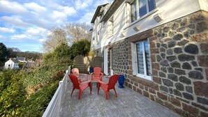 Un edificio a due piani con facciata in pietra e un balcone con sedie rosse e un tavolo.