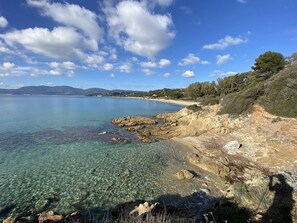 Eine Küstenlandschaft mit klarem Wasser, felsigen Ufern und Bergen in der Ferne.