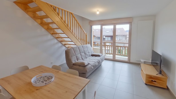 A modern living room with a wooden staircase, a sofa, a dining table, and a TV stand. - New apartment for 8, near center, Les Rousses (Les Rousses)