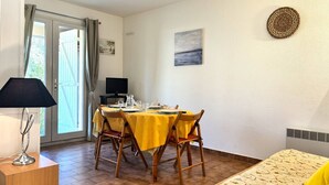Ein Essbereich mit einem Tisch für vier Personen, einem Fernseher und einem Gemälde an der Wand.