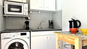 Eine kompakte Küche mit Waschmaschine, Mikrowelle und Kaffeemaschine.