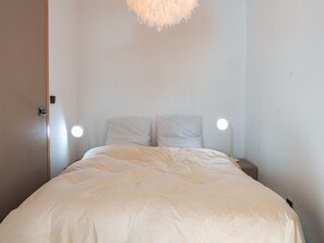 A minimalist bedroom with a bed, two bedside lamps, and a door. - Ski-in/ski-out apartment Val Thorens - 6 people, central and convenient (Val Thorens)