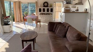 Ein modernes Wohnzimmer mit einem braunen Sofa, einem runden Couchtisch und einem Essbereich inklusive Tisch und Stühlen.
