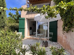 A patio with a table and chairs, a white umbrella, and a view of the interior through a glass door. - 3-Bedroom House with Private Pool and Sea View (La Croix-Valmer)