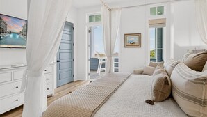Ein Schlafzimmer mit einem Bett, einem Fernseher, einem Fenster und einem Balkon.